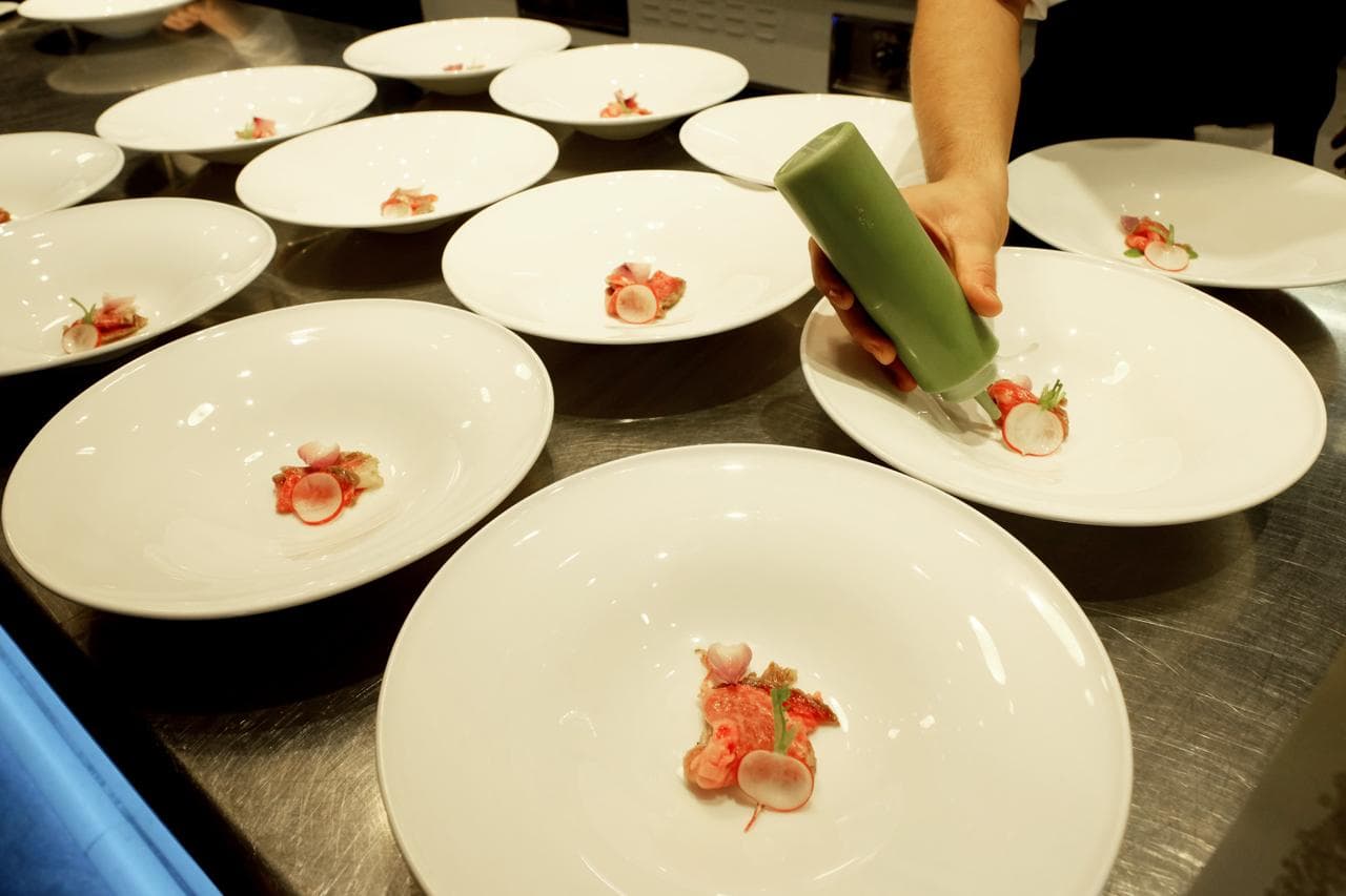 Le mise en place del piatto di Wagyu rifinite una a una sul passe, durante l'evento in Alice Ristorante.