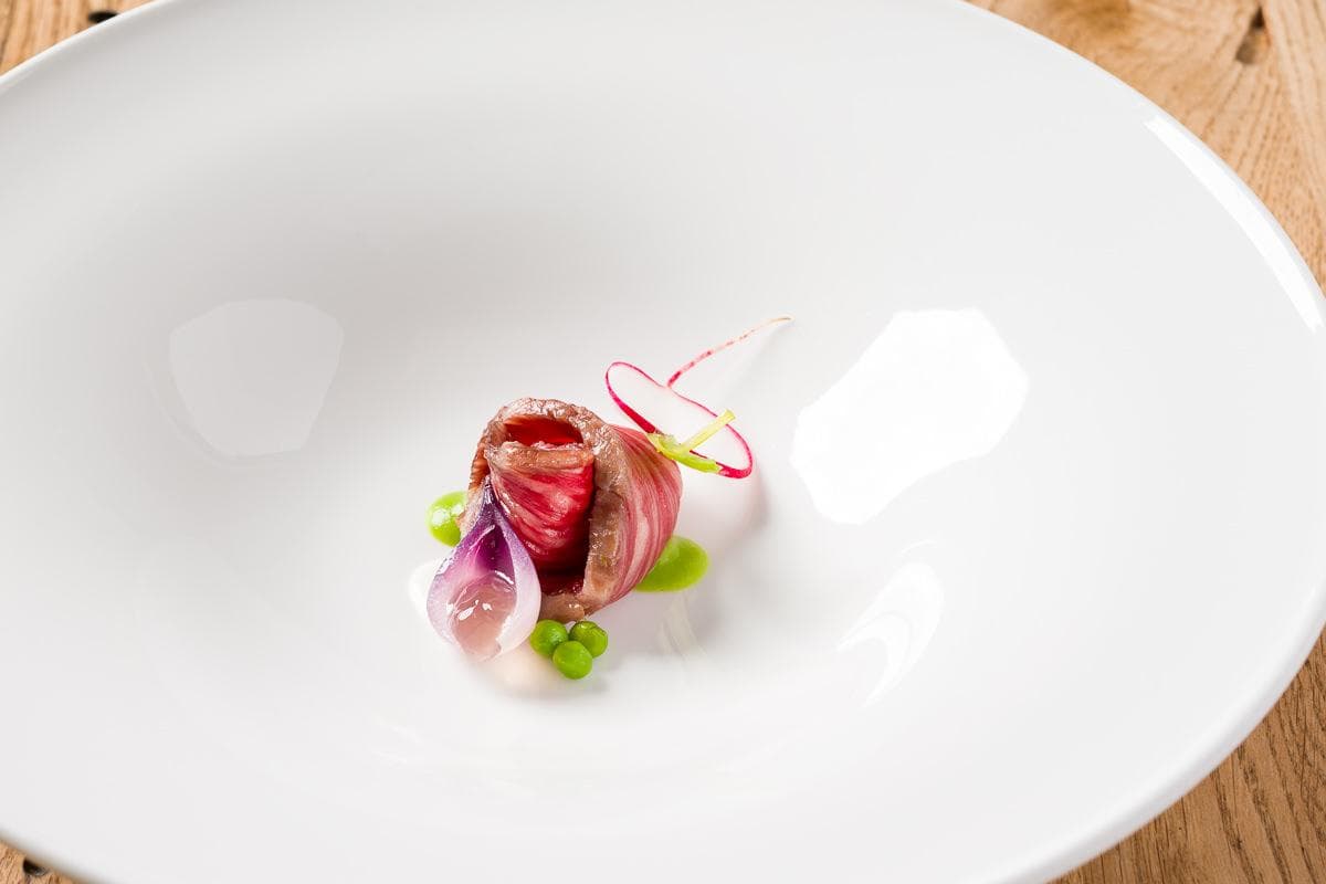Il piatto finito: rotolino di Wagyu con ravanello, cipolla marinata e piselli.