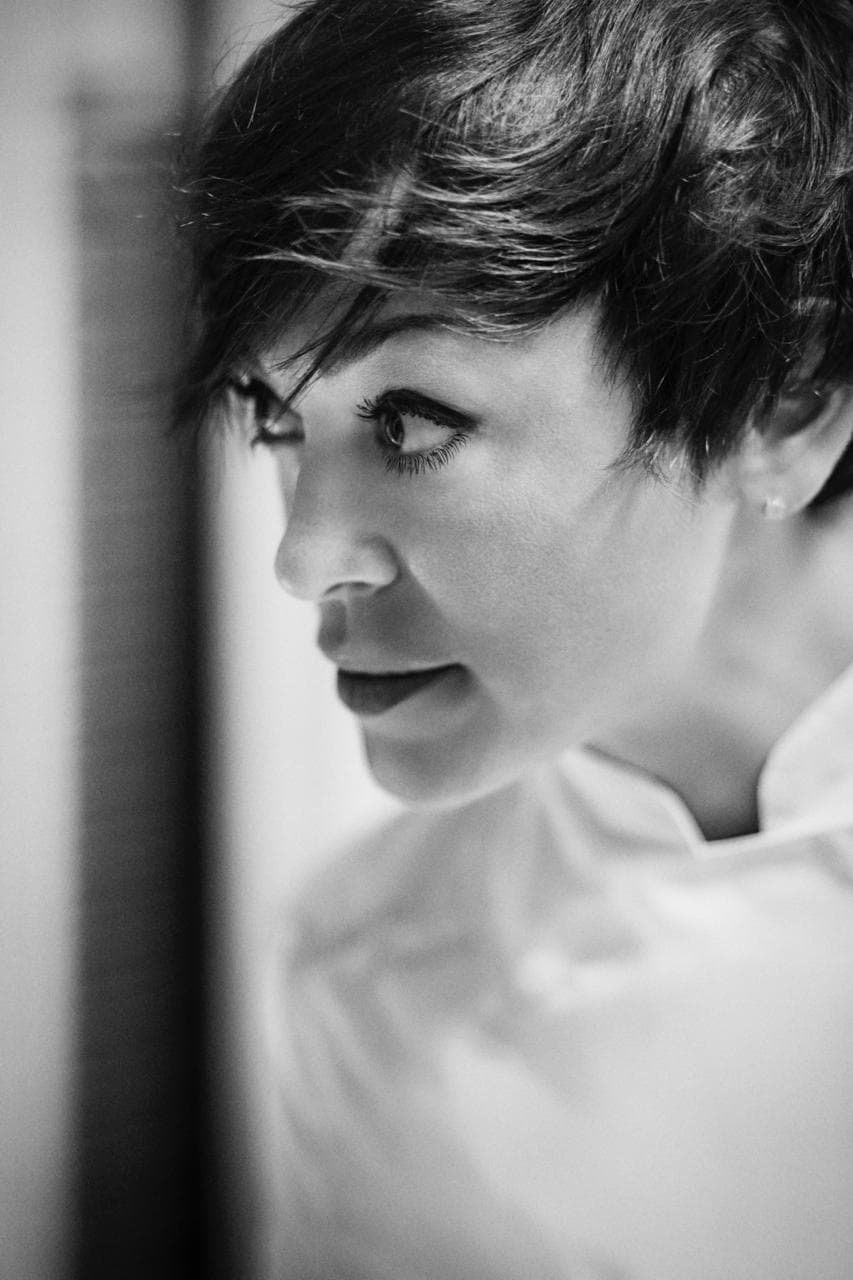Ritratto in bianco e nero di Rubina Rovini in giacca da chef, di profilo.