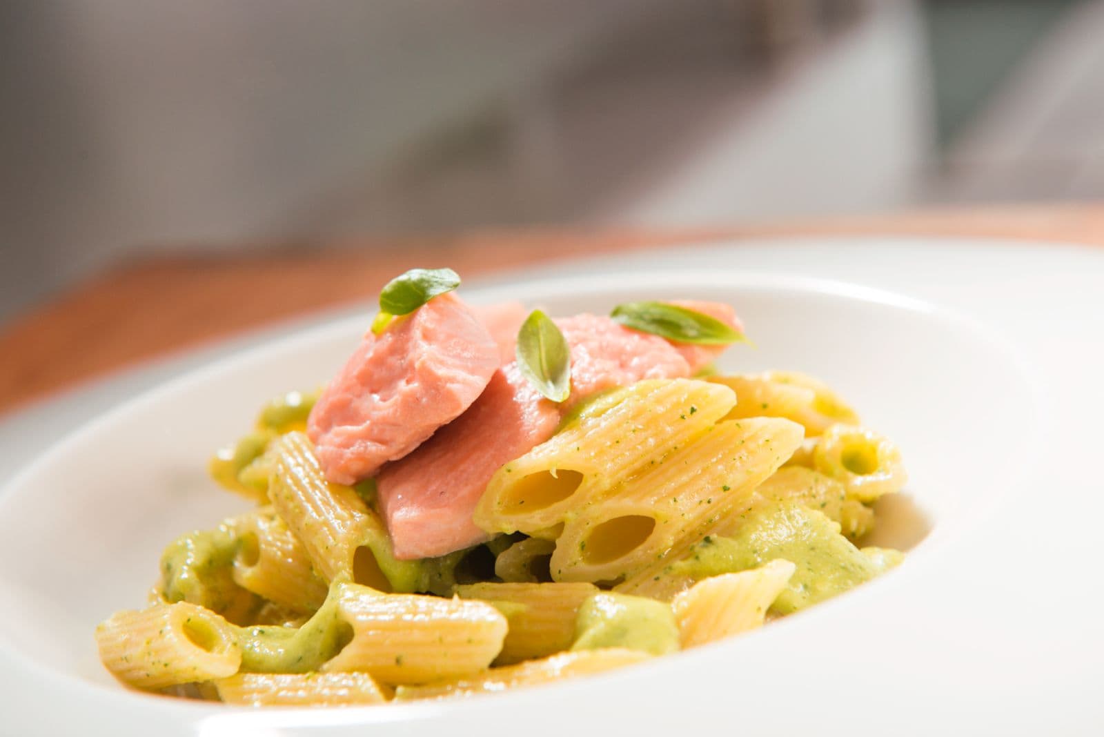 Pennette con crema di verdure e salmone, servite nel piatto bianco.