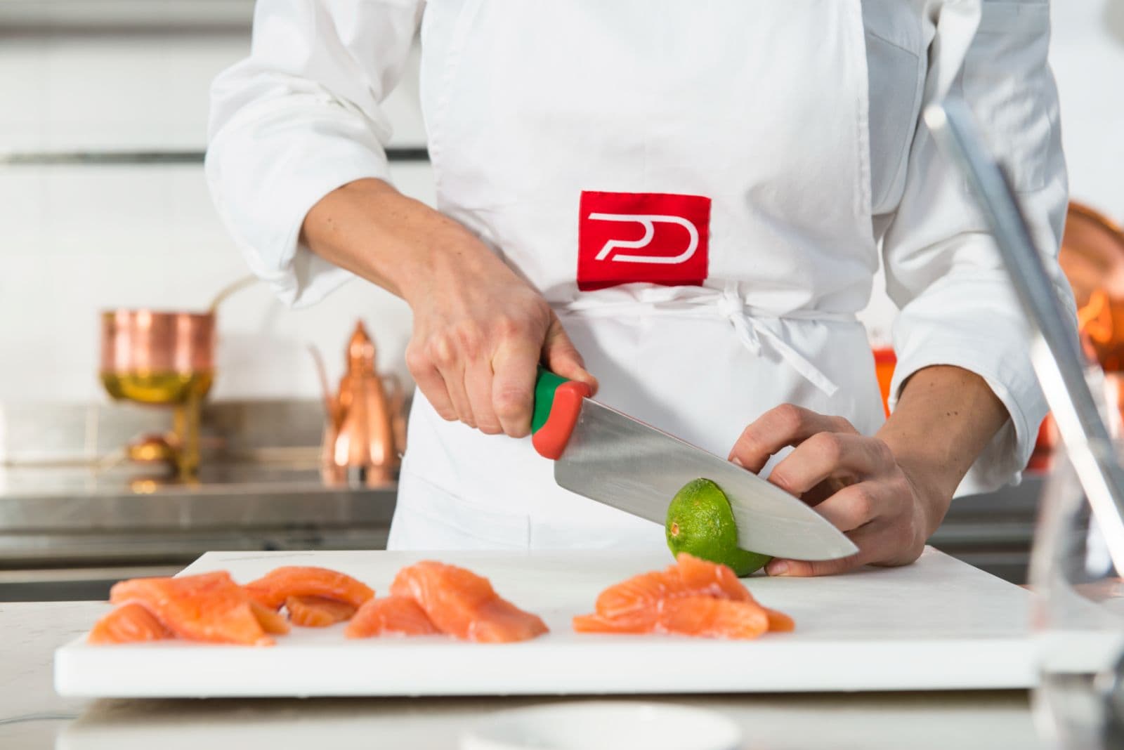 Le mani di Rubina Rovini tagliano il salmone sul tagliere.