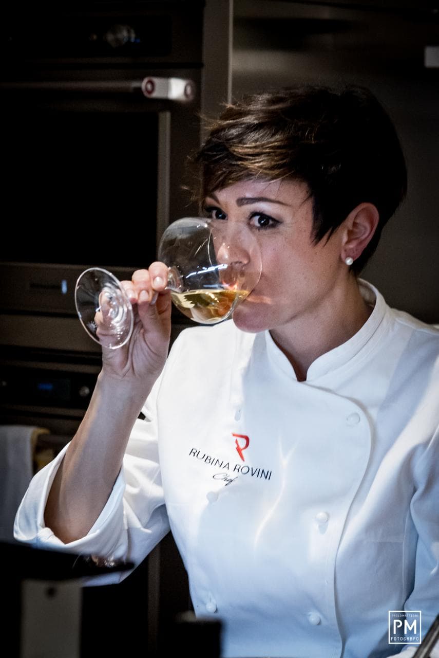 Rubina Rovini assaggia un calice di vino bianco in cucina.