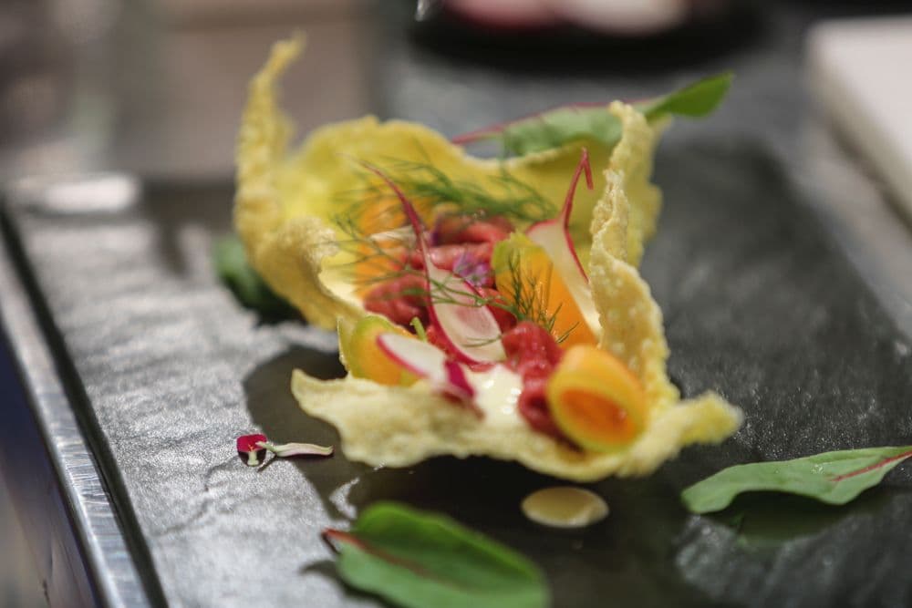 Piatto d'autore con melone, foglia croccante e verdure.