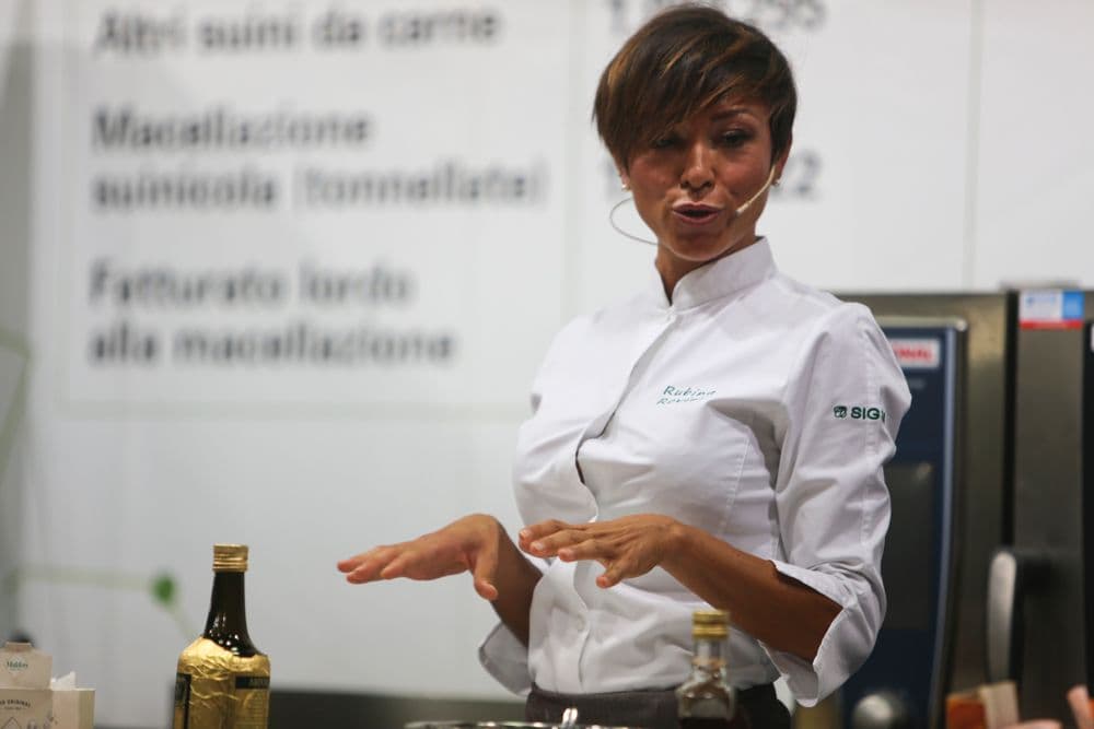 Rubina Rovini presenta i dati del consorzio davanti al pannello espositivo.