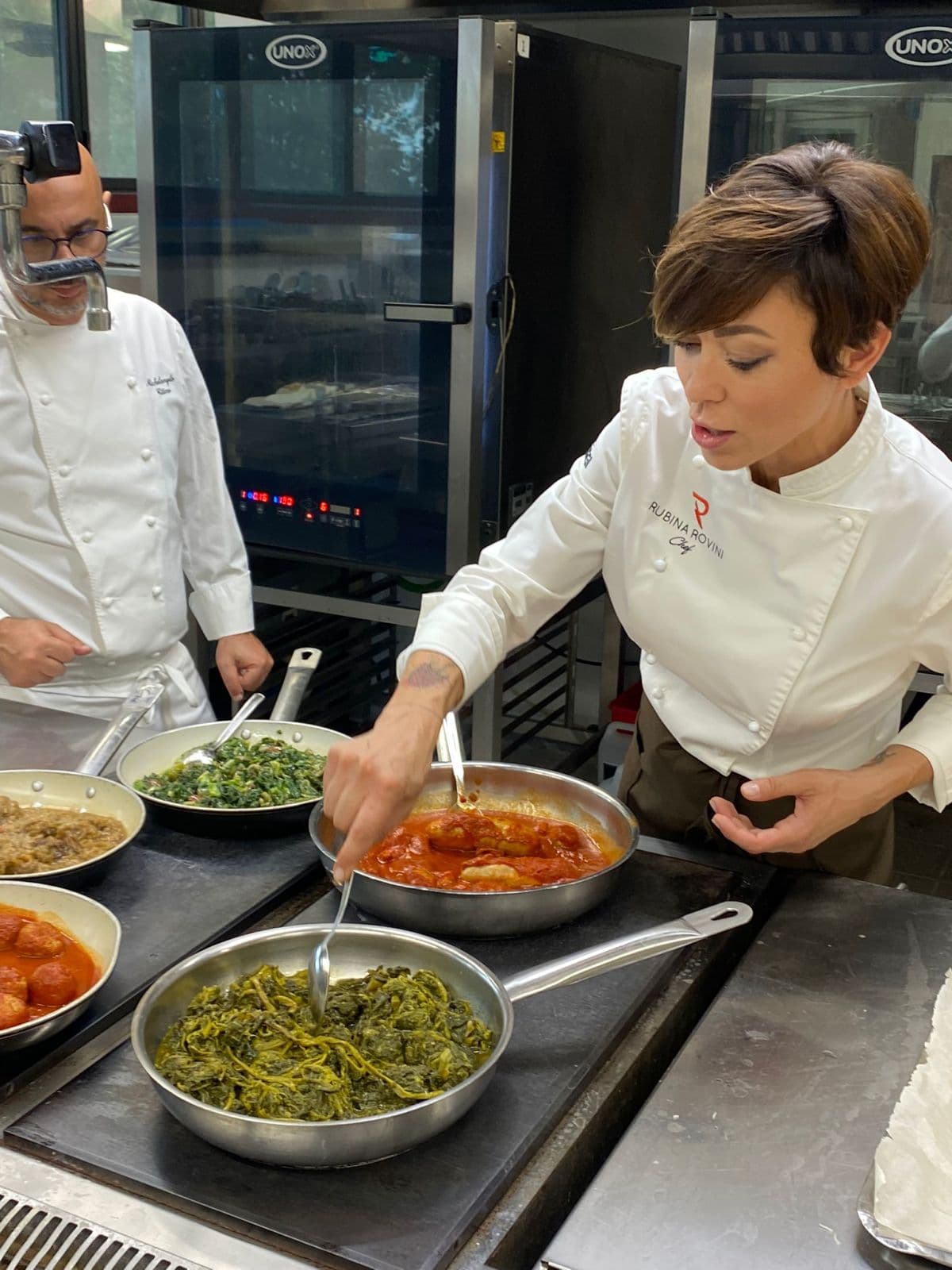 Rubina Rovini assaggia le preparazioni con un collega nella cucina di produzione.