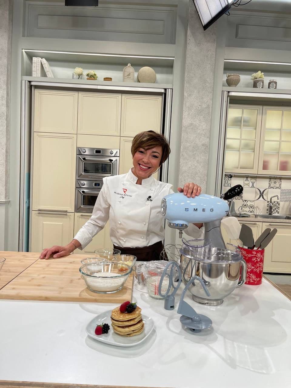 Rubina Rovini presenta l'impastatrice SMEG accanto ai pancake appena preparati.