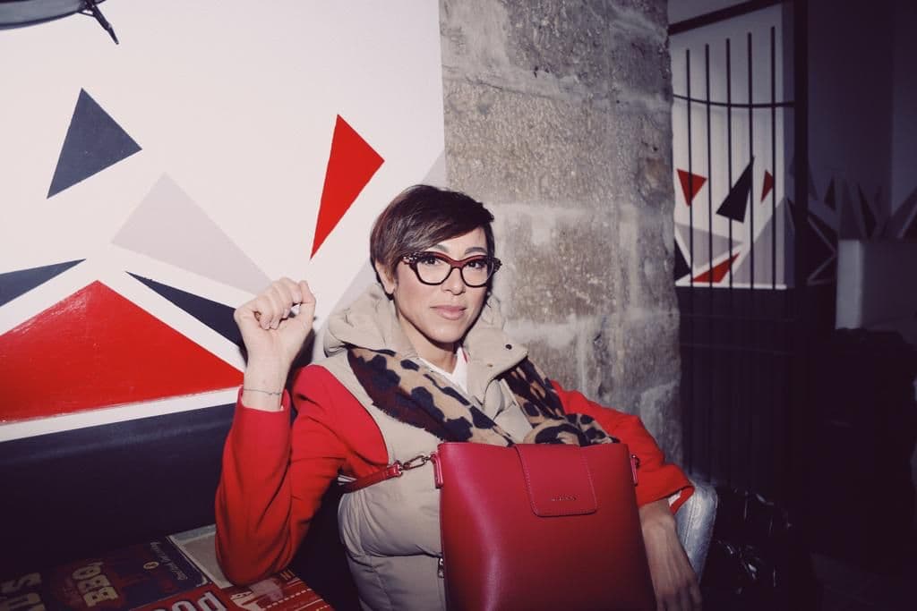 Rubina Rovini seduta sulla poltrona rossa davanti alle grafiche del TEDx di Rieti.