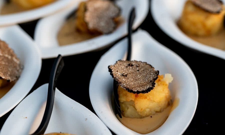 Assaggi con scaglie di tartufo nero serviti in cucchiai di porcellana.