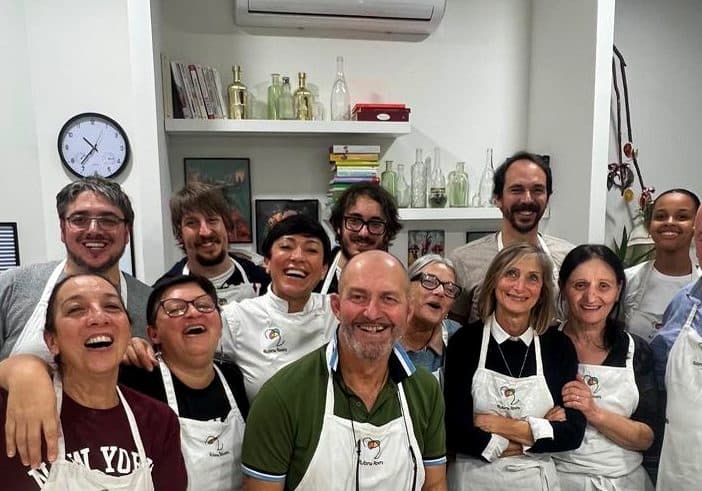 I partecipanti di una serata in RADICI Lab ridono insieme attorno al banco di lavoro.